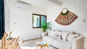 Un salon avec un canapé beige, une petite table basse en bois et un élément décoratif fixé au mur.