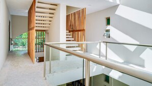Un intérieur moderne avec une balustrade en verre, un mur à lattes en bois et un escalier menant à un espace extérieur.