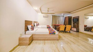 A hotel room with a large bed, a desk, two chairs, a TV, and a ceiling fan. - Hotel Lakshmi Palace (New Delhi)