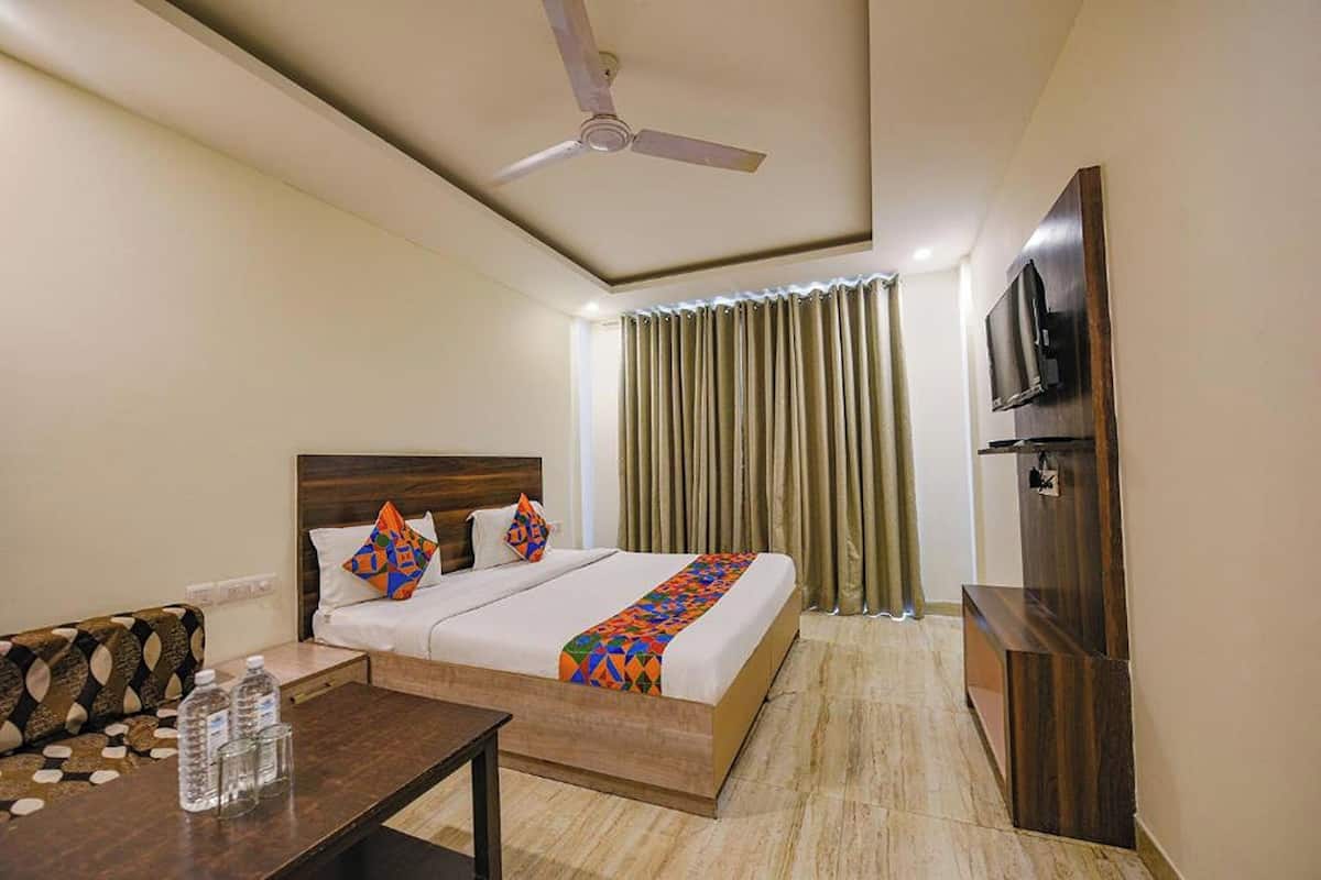 A hotel room with a bed, a TV, a desk, and a ceiling fan.