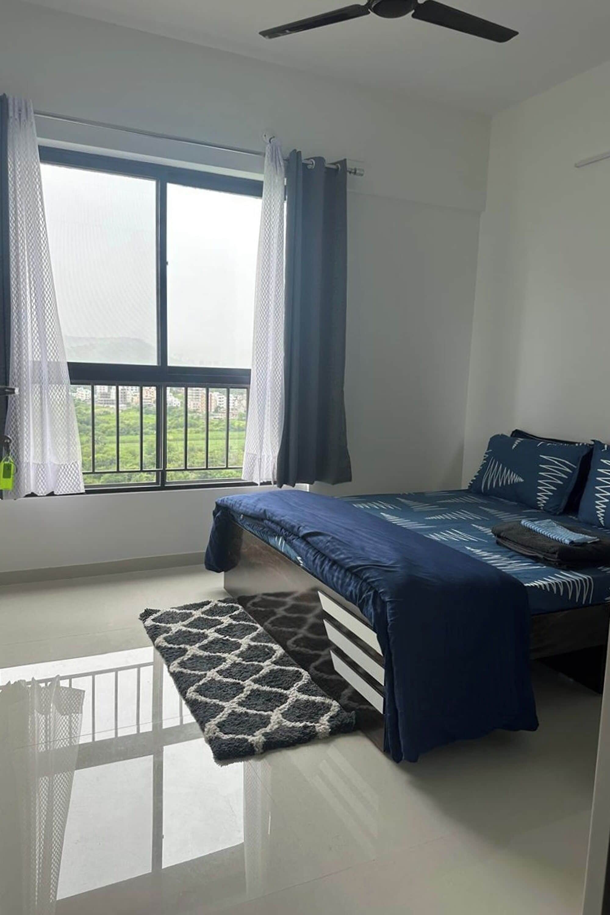 Une chambre à coucher avec un lit, une fenêtre et un ventilateur de plafond.