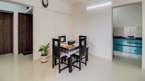 Zona pranzo con tavolo apparecchiato per quattro persone, una pianta in vaso e una ventola a soffitto.
