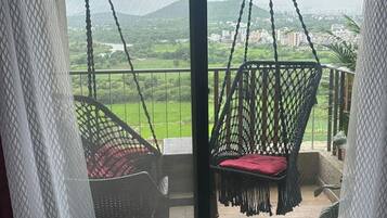 Un balcón con dos sillones colgantes y vistas a un paisaje verde.