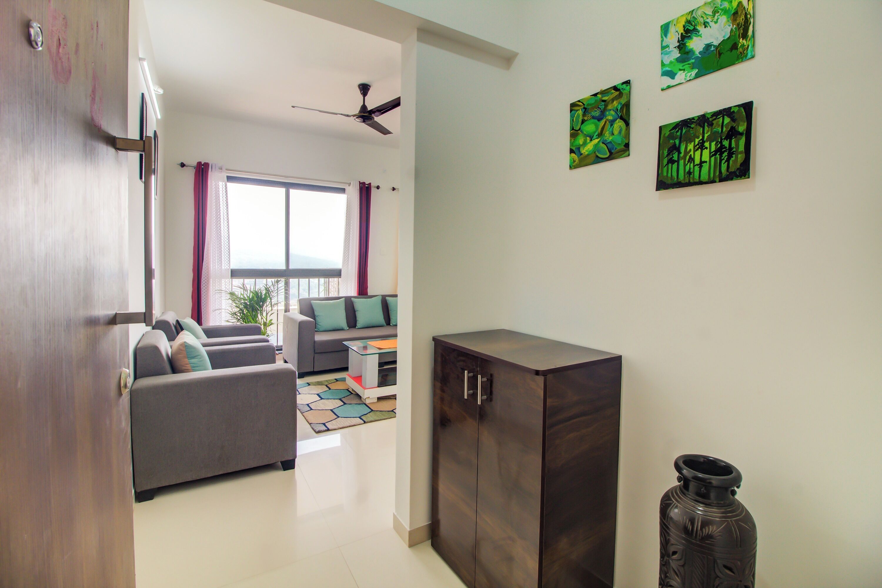 Un salon moderne avec un canapé, une table basse et un meuble. Il y a trois tableaux accrochés au mur.