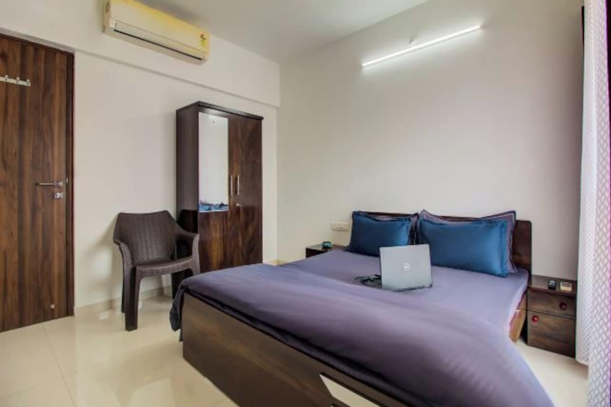 Un dormitorio con una cama, un escritorio, una silla, un armario y aire acondicionado.