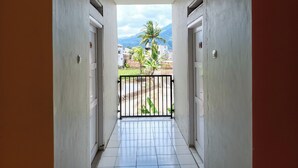 A corridor with a tiled floor leading to a balcony with a metal railing. - Khanza Costel Syariah (Karangtengah)