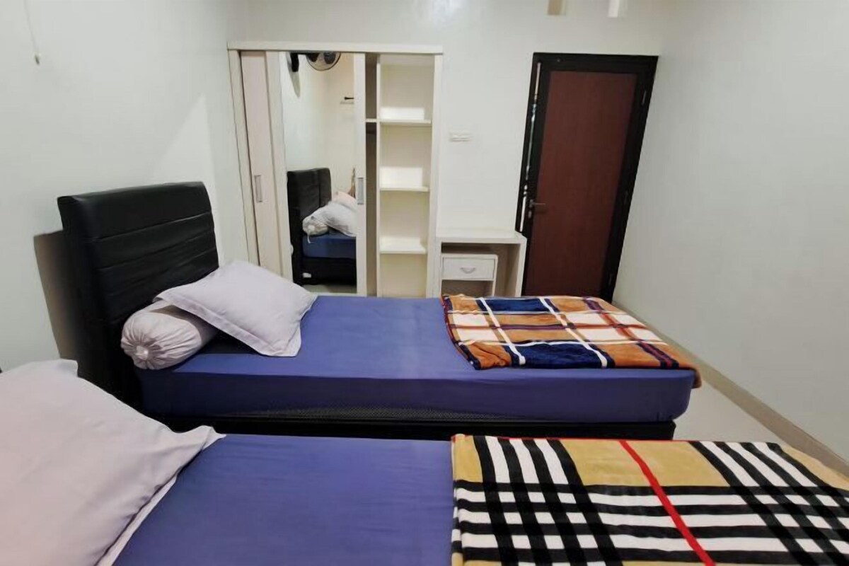 Una habitación pequeña con dos camas, un armario y un escritorio.