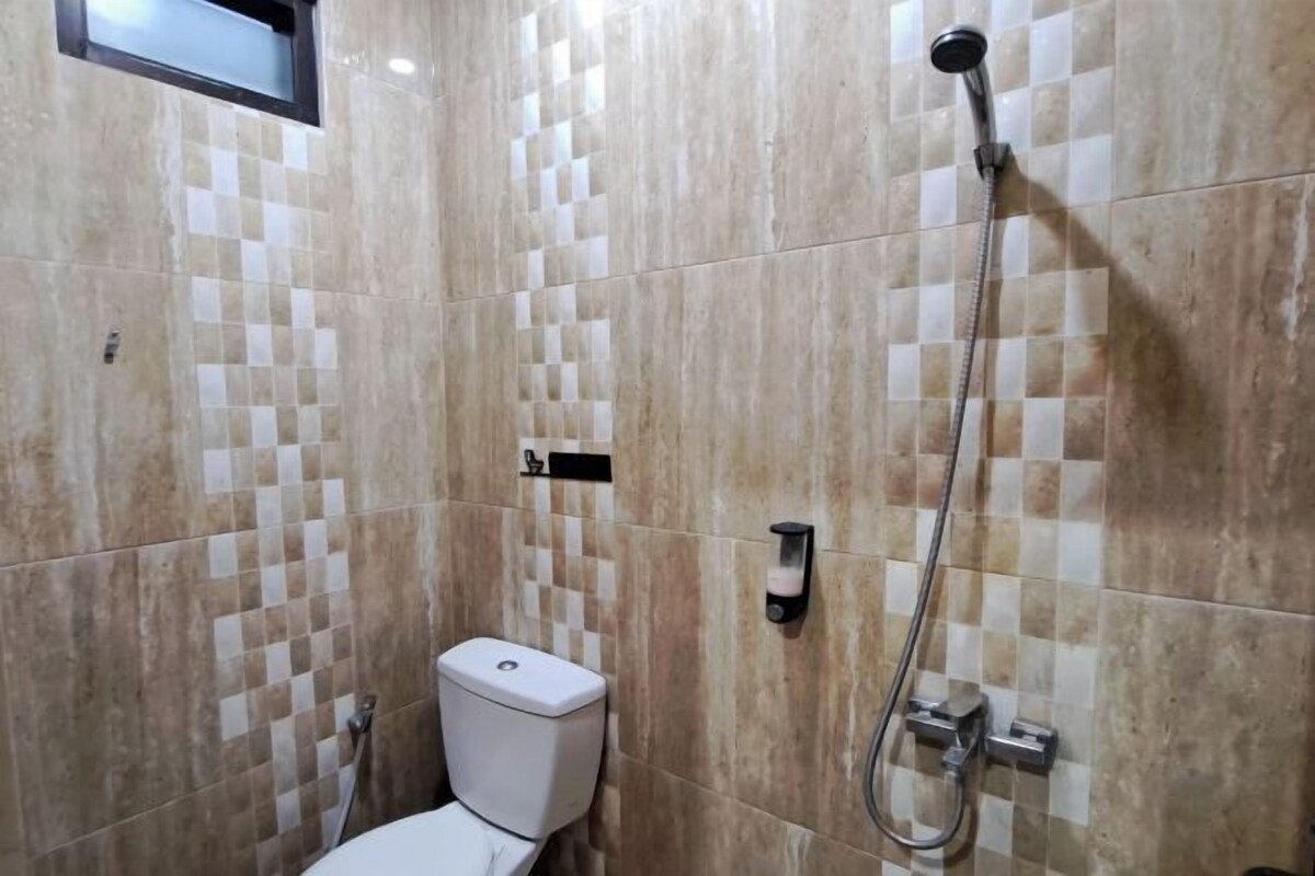 Un baño con inodoro, ducha y pared con azulejos.