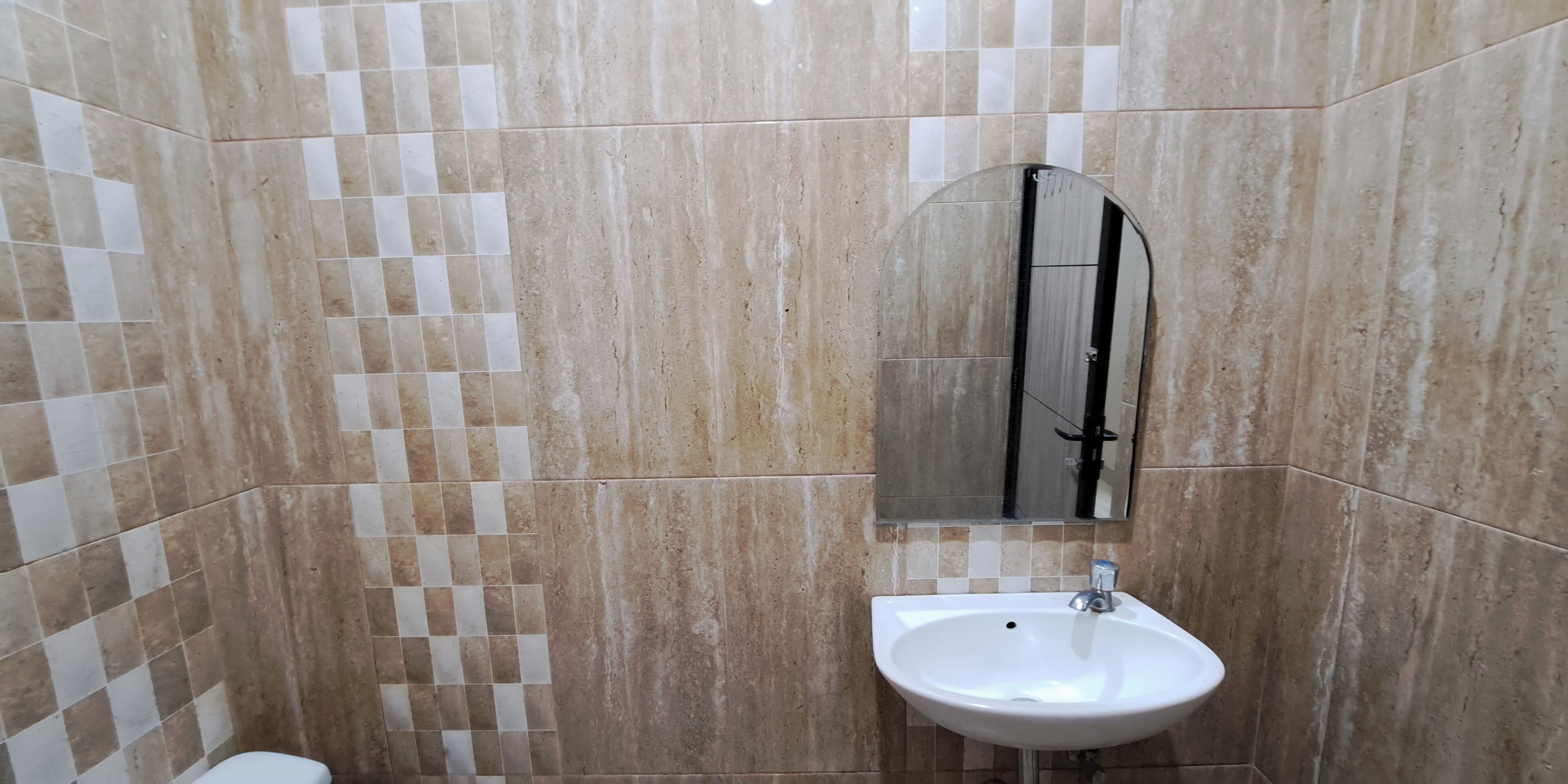 A bathroom with a tiled floor, a sink, and a mirror.