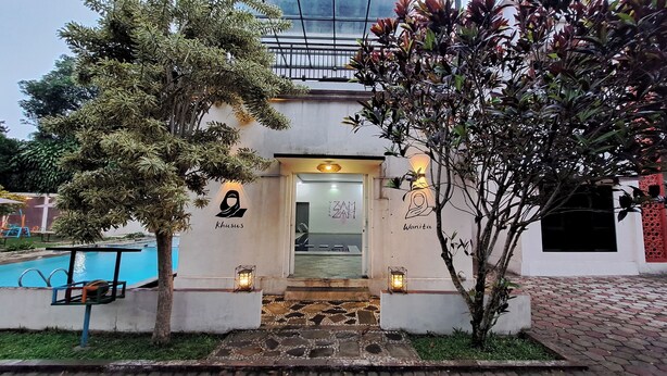 A building entrance with a pool, surrounded by trees and a brick pathway. - Villa Zam Zam Puncak (Cisarua)