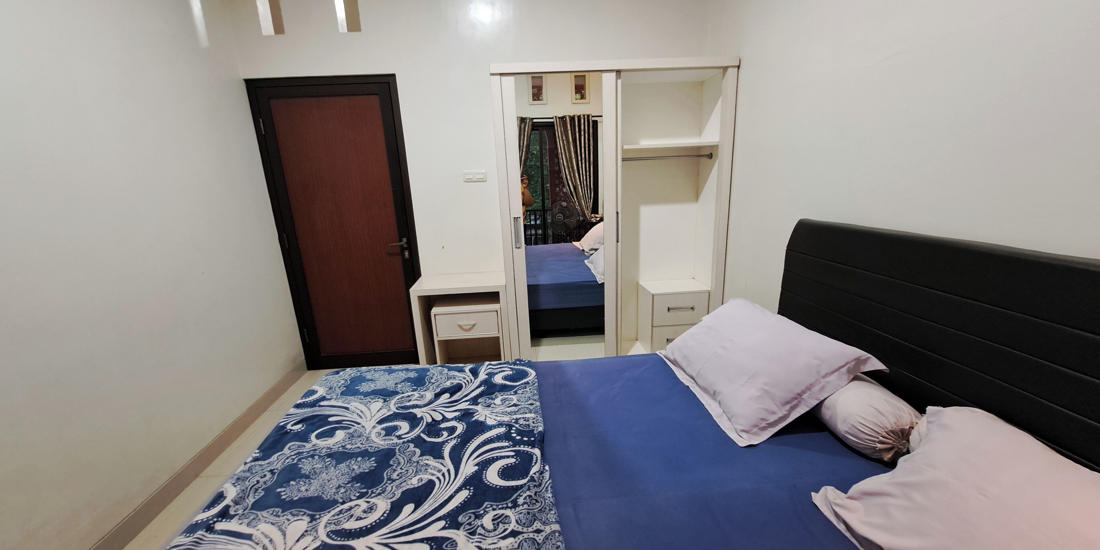 A bedroom with a bed, a wardrobe, a desk, and a chair.