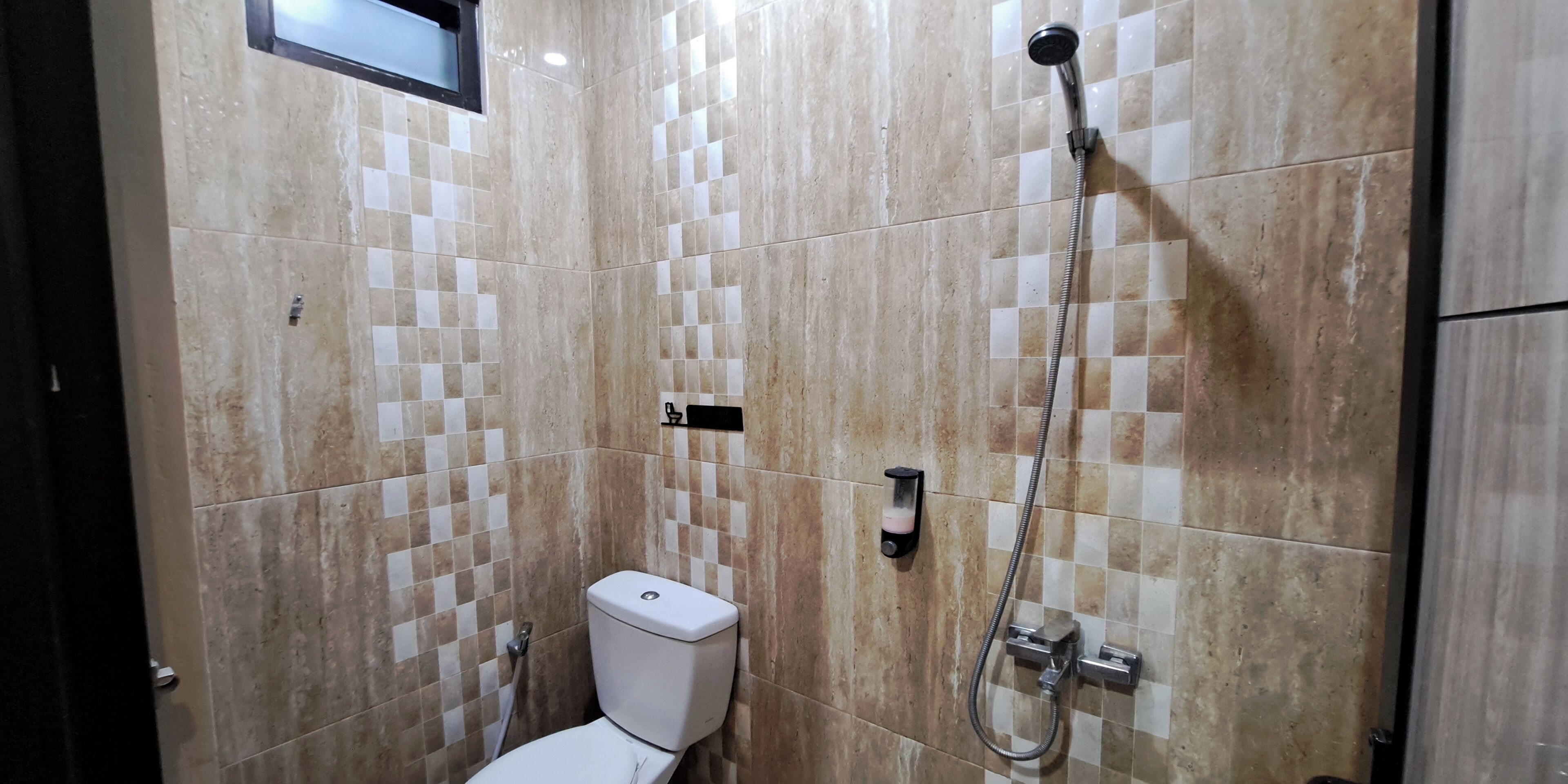 A bathroom with a toilet, a shower, and tiled walls.