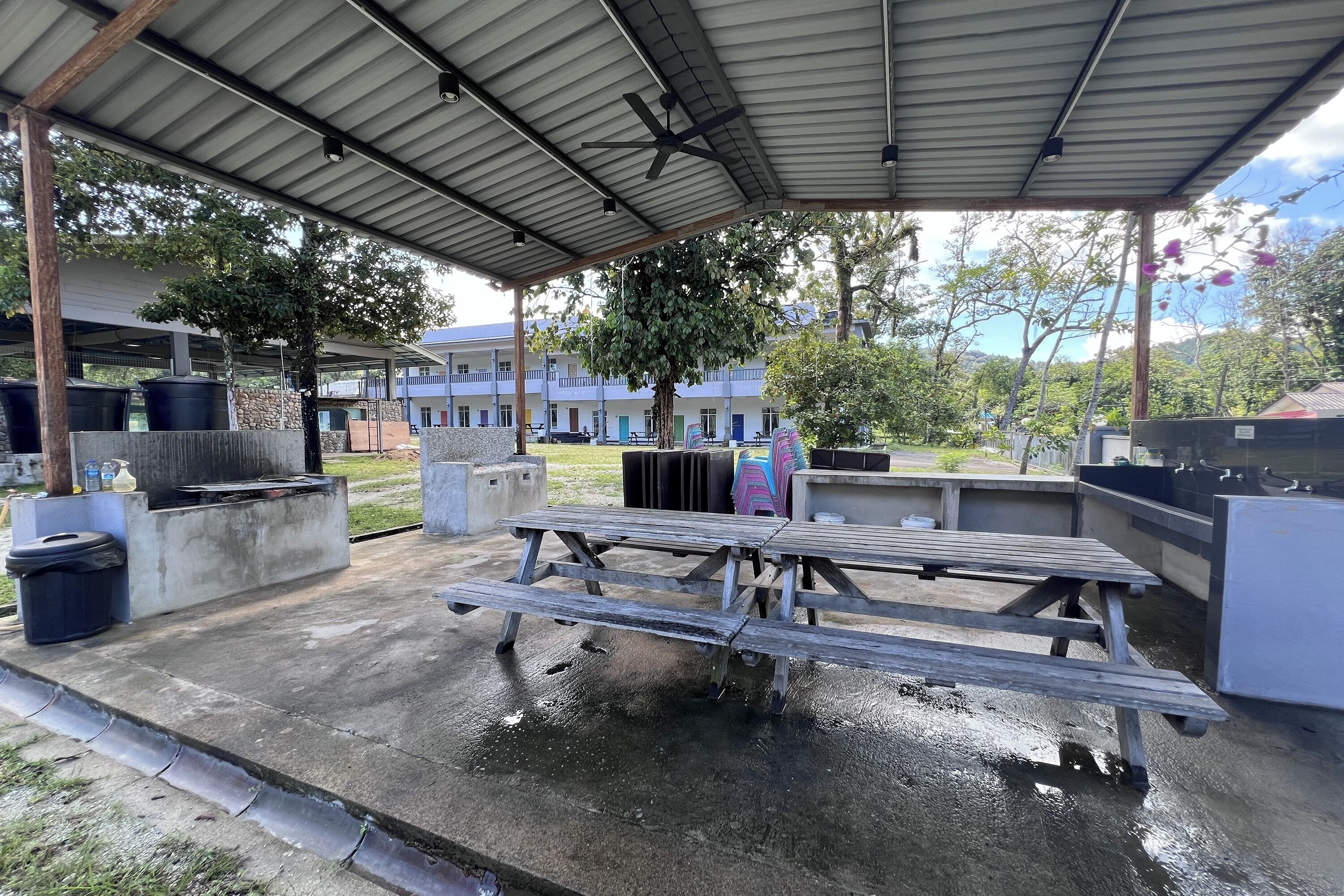 Un espacio al aire libre cubierto con una mesa de picnic, botes de basura y un dispensador de agua.