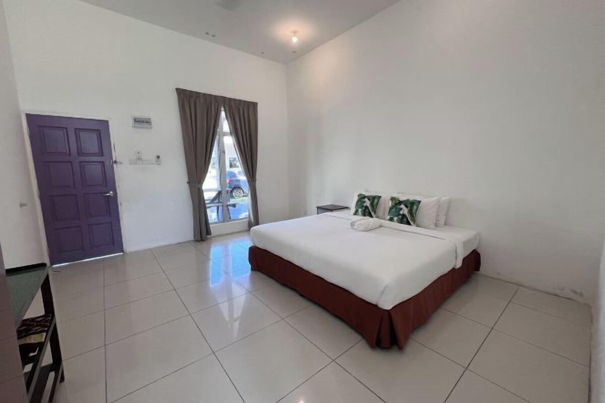 A hotel room with a bed, a table, and a window with curtains.