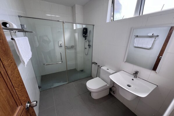 Ein modernes Badezimmer mit einer Duschkabine aus Glas, einer weißen Toilette und einem Waschbecken mit Spiegel.