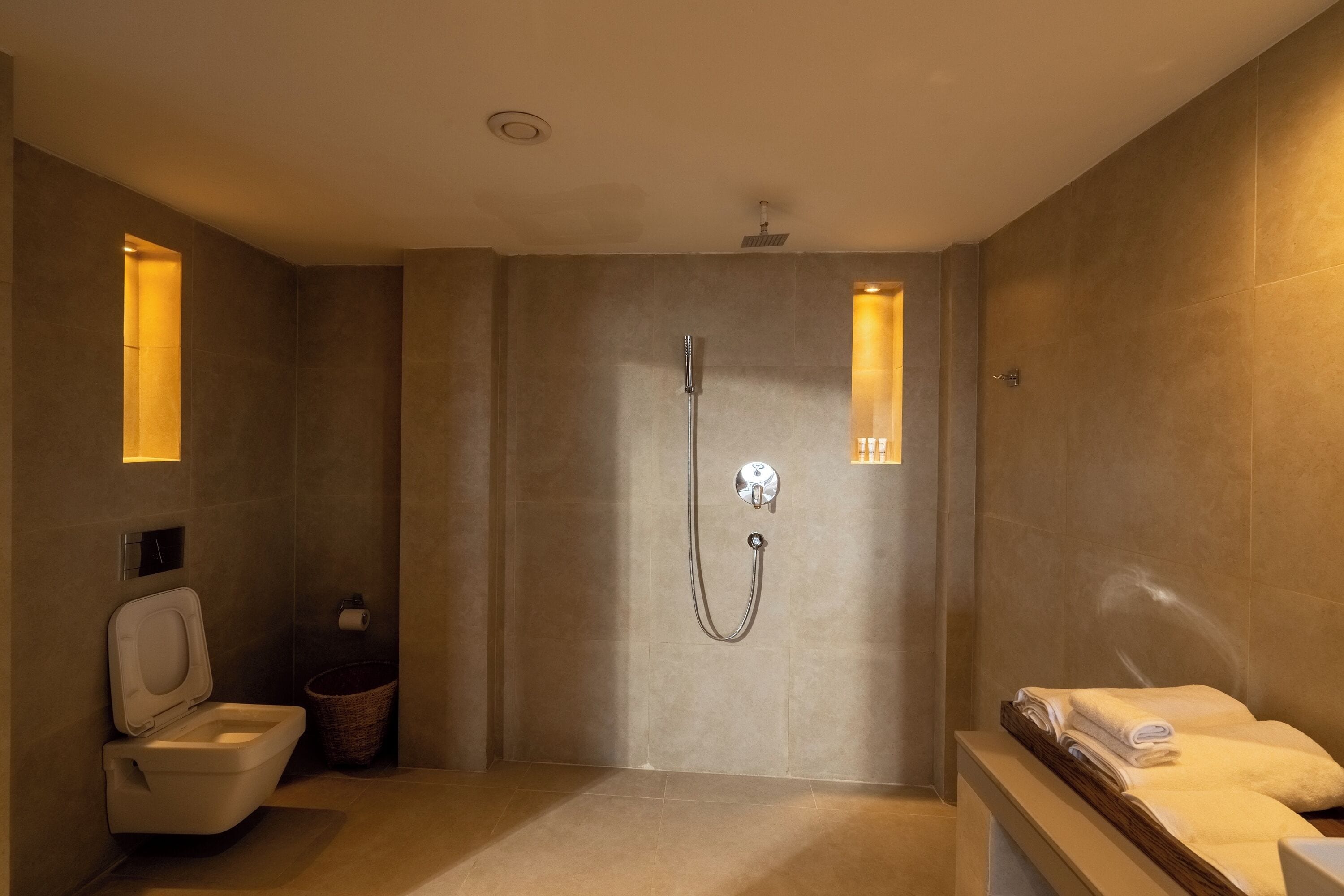 Une salle de bain moderne équipée d’une douche, de toilettes et d’un meuble-lavabo avec des serviettes.