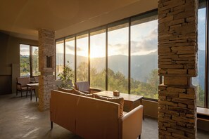 A spacious room with a large window, stone pillar, and a sofa. - Nana Mountain Resort Mt. Annapurna View (Dhampus)