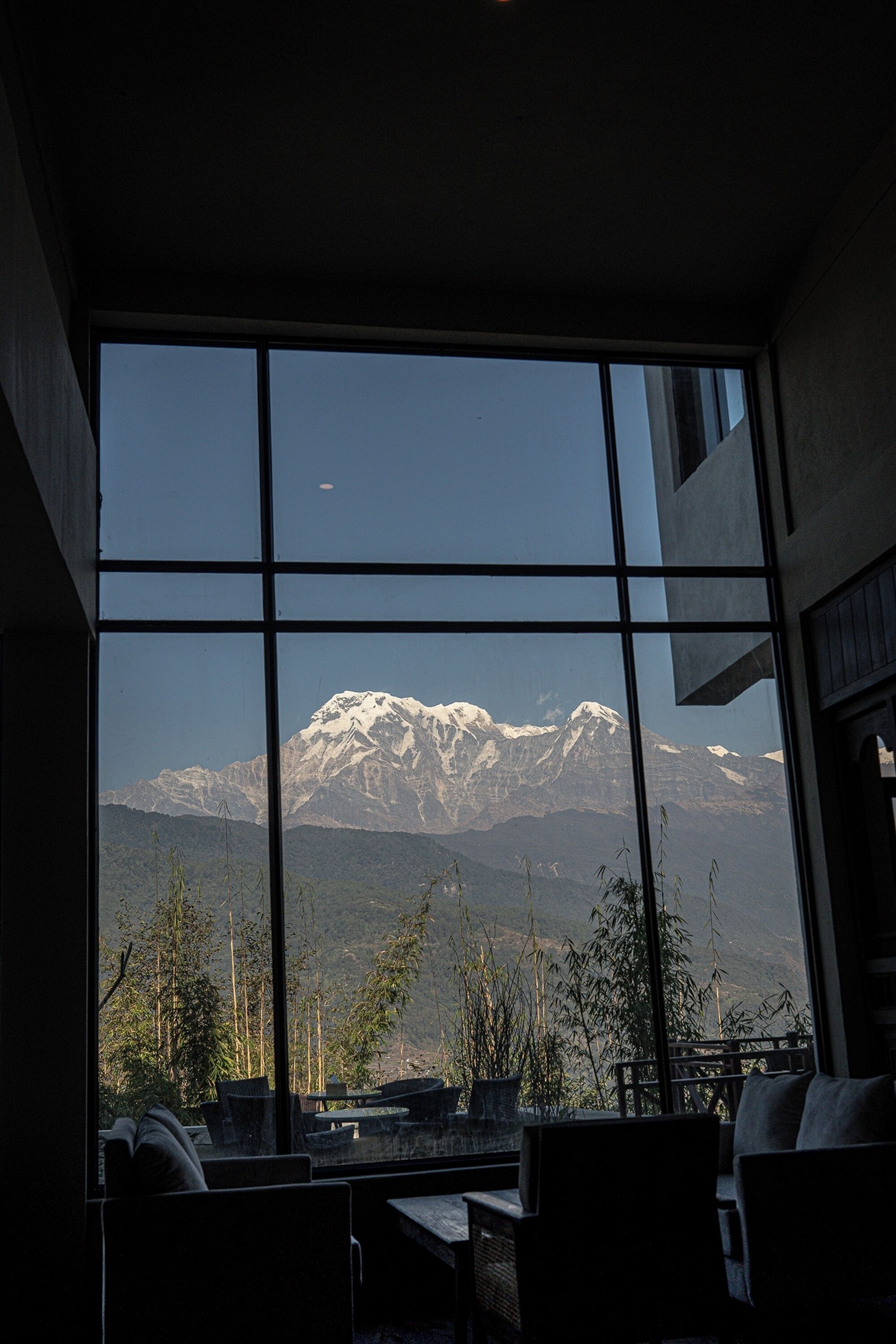 A room with a large window offering a view of a snow-capped mountain.