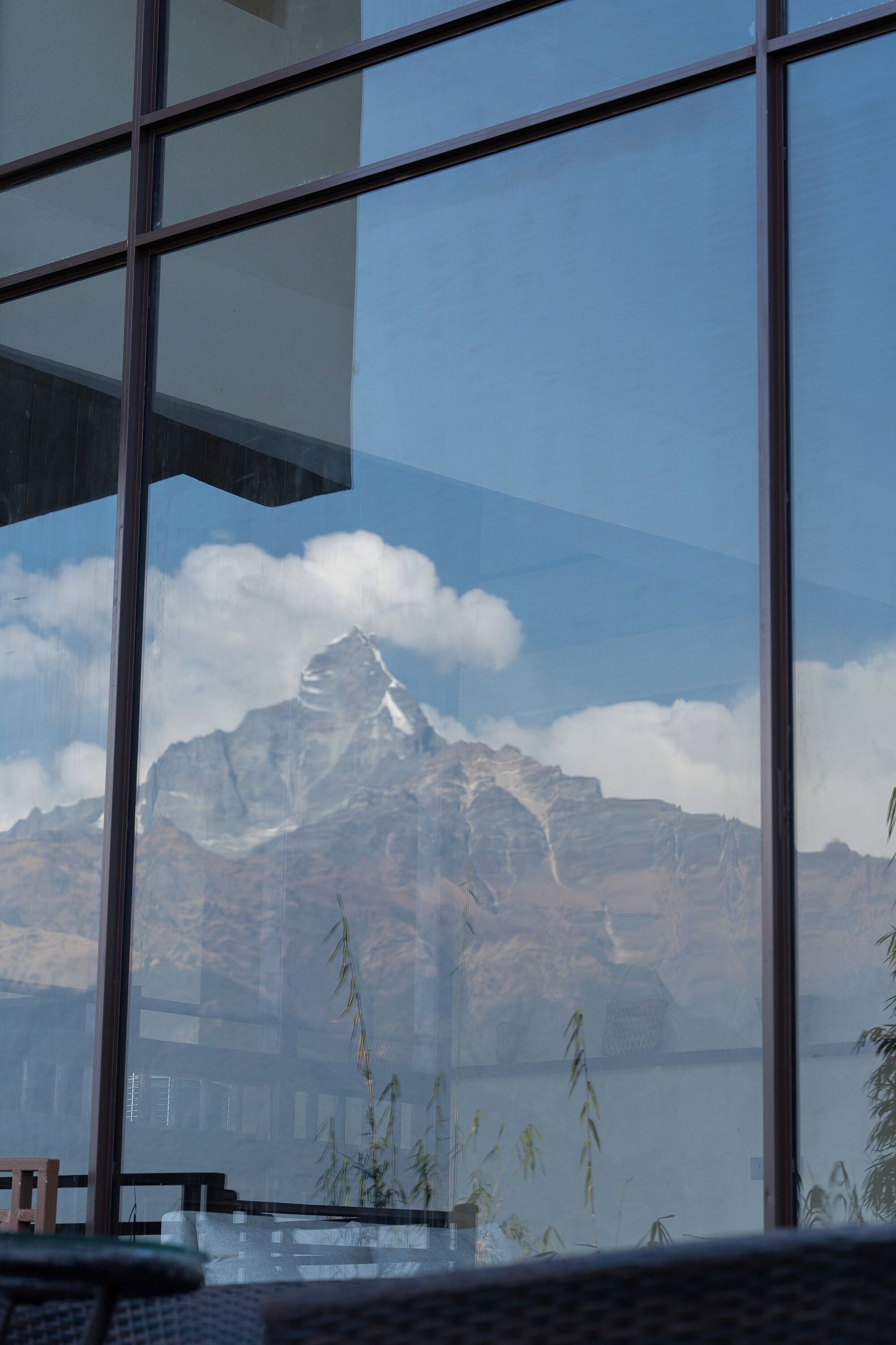 Une vue à travers une fenêtre, avec une montagne en arrière-plan.