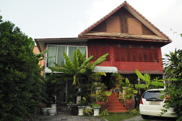 A traditional house with a red facade, a tiled roof, and a front porch with potted plants. - 64 Sweet Home Dusit Bkk (Bangkok)