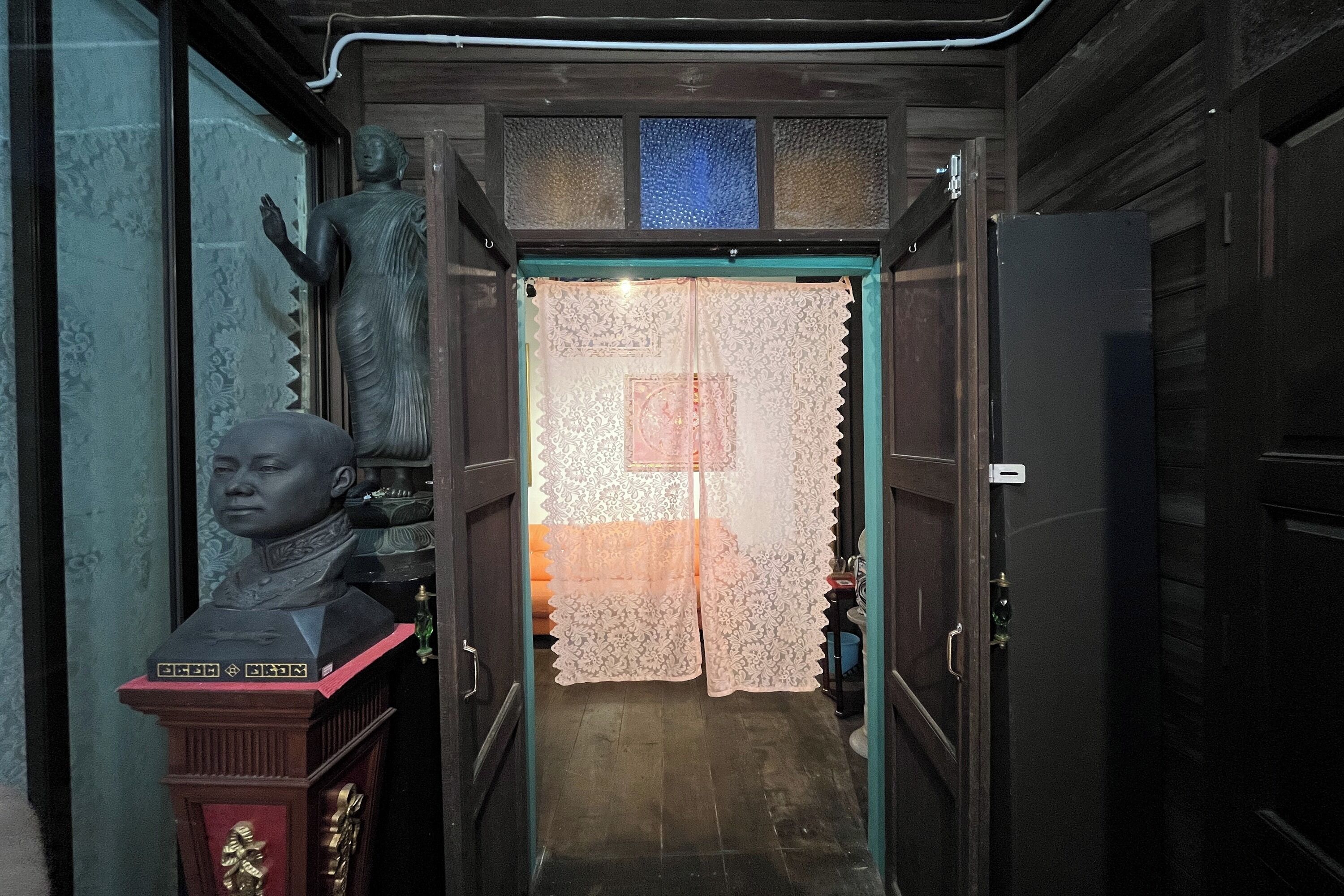 A hallway with a statue, a decorative door, and a refrigerator.