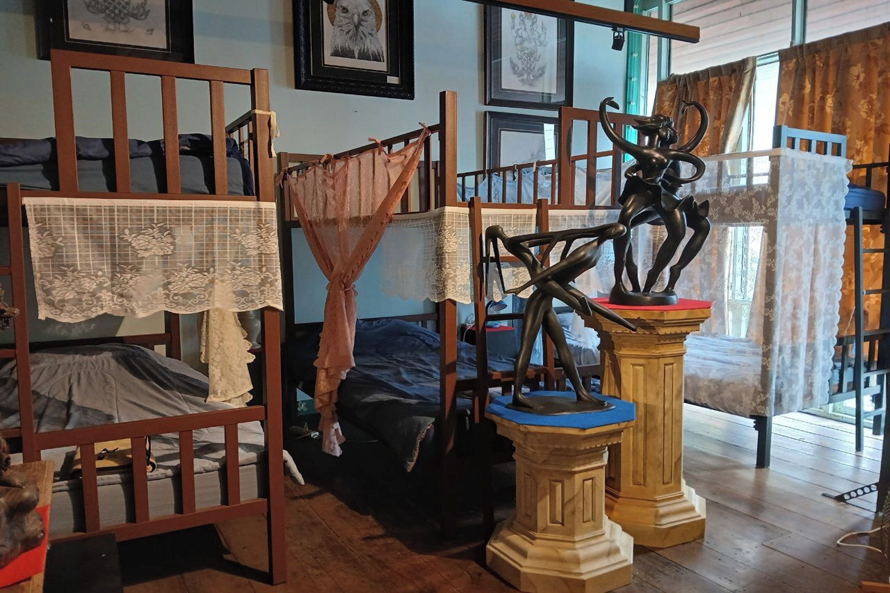 A room with bunk beds, a statue, and framed artwork on the walls.