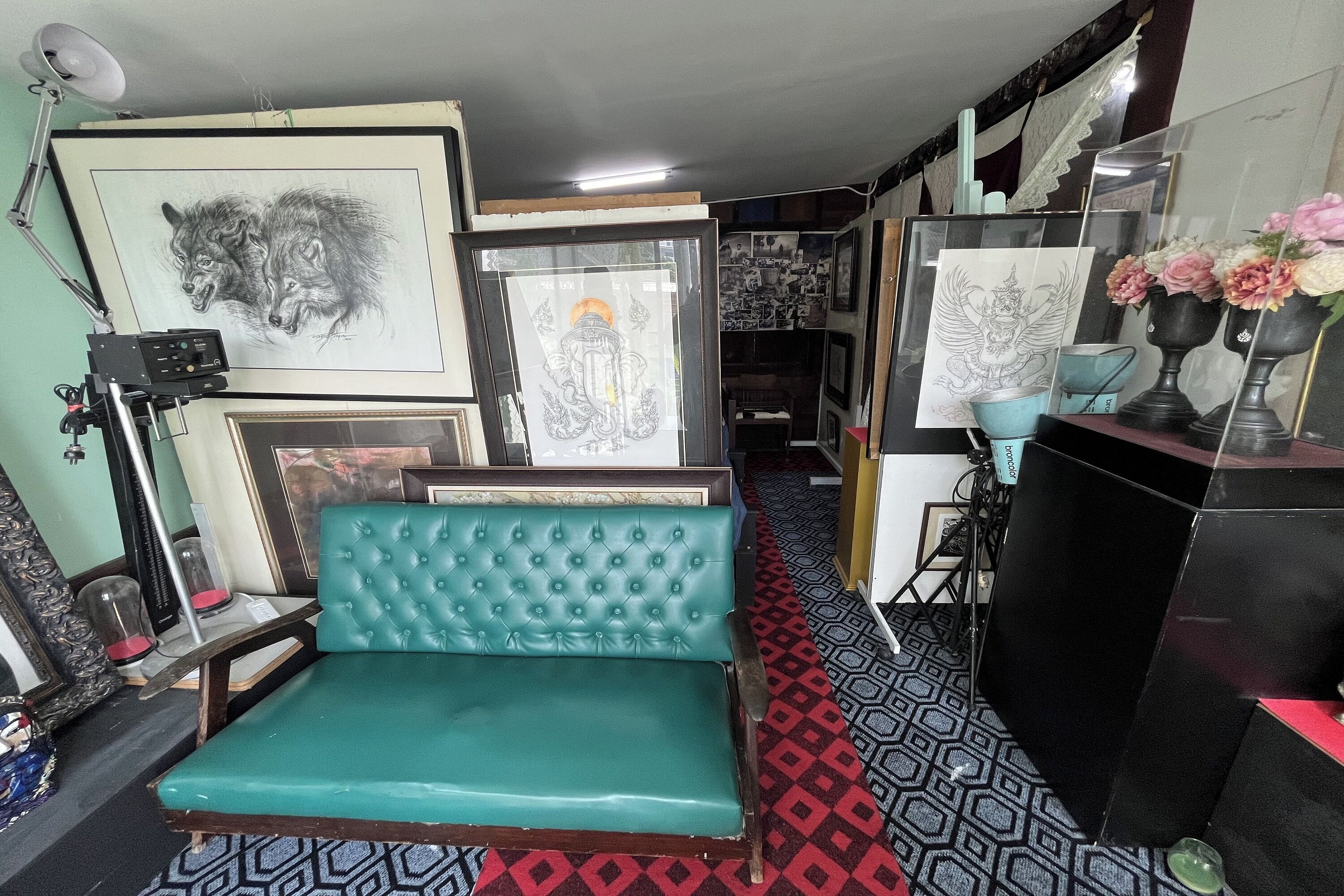A room with a teal upholstered bench, framed artwork on the walls, and a patterned floor.