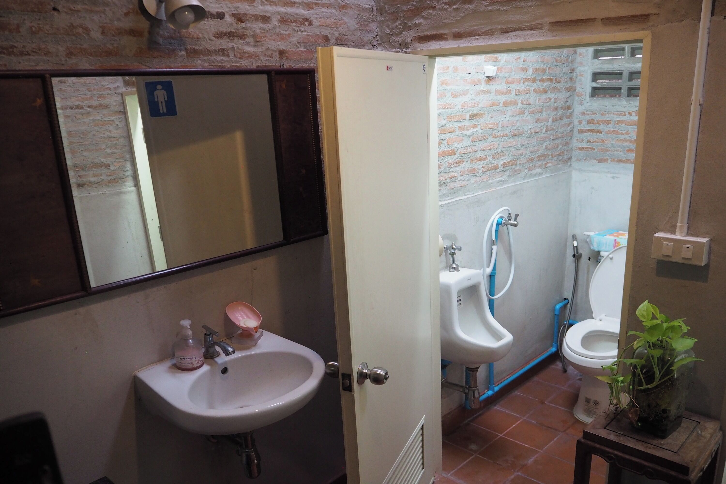 A bathroom with a sink, mirror, and two urinals.