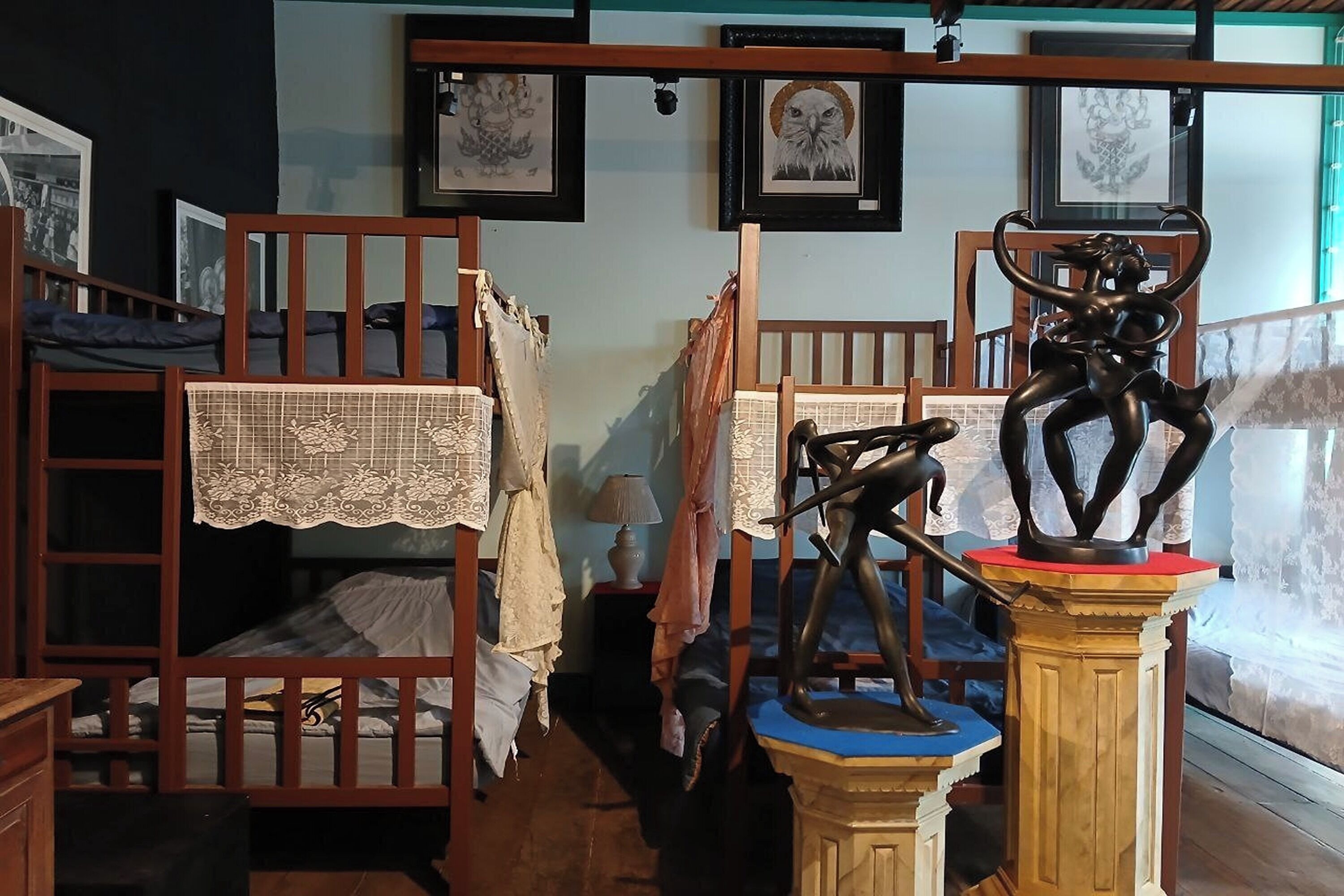 A room with bunk beds, a statue, and framed artwork on the wall.