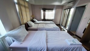 Een hotelkamer met twee bedden, een raam met gordijnen, een airconditioning en een deur.