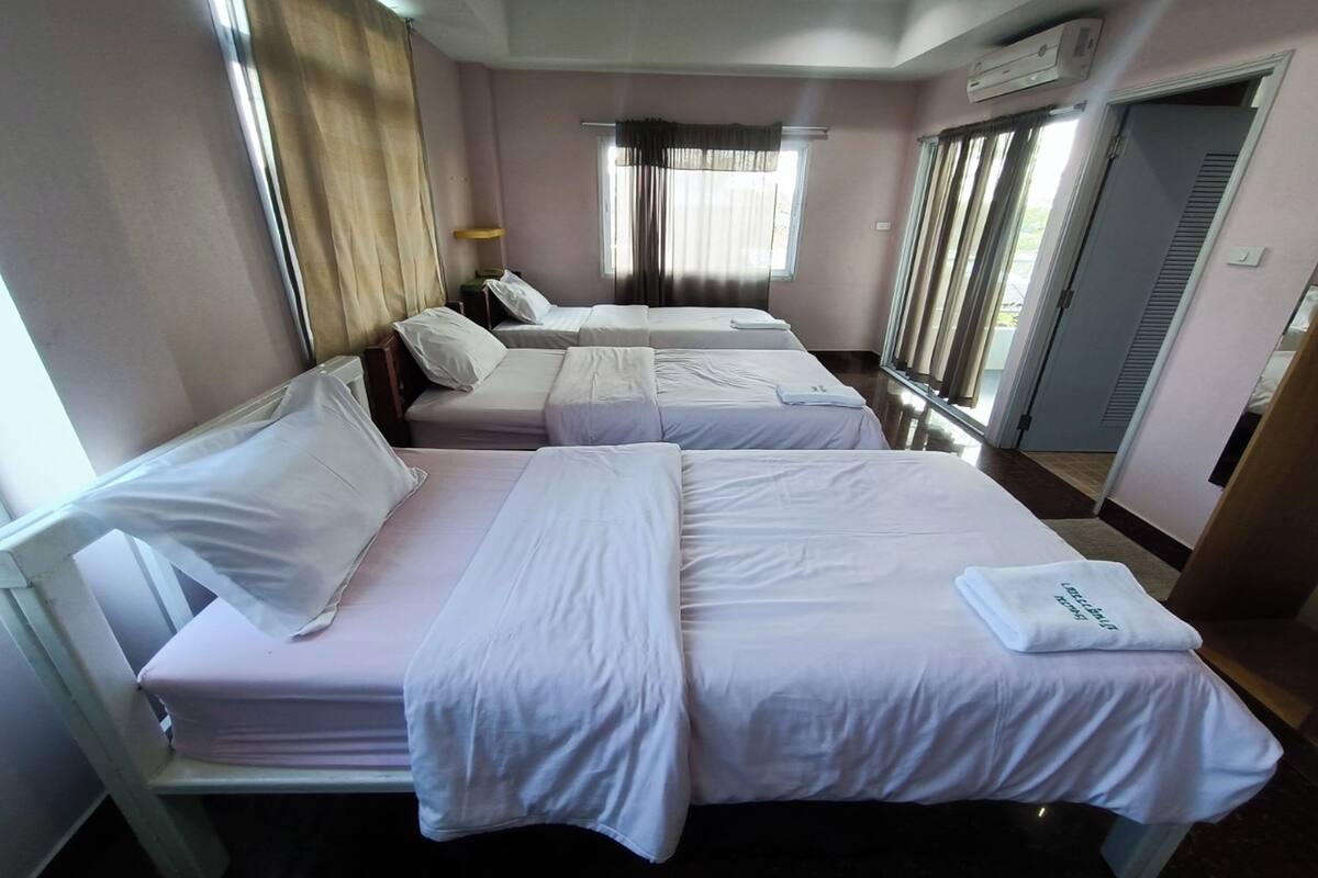 Une chambre d’hôtel avec deux lits, une fenêtre avec des rideaux, un appareil de climatisation et une porte.