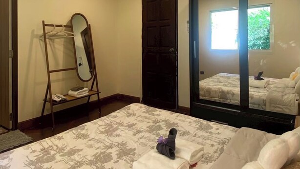A hotel room with a bed, a mirror, a wardrobe, and a window. - Jaokhun Panorama Villas, Patong (Patong)