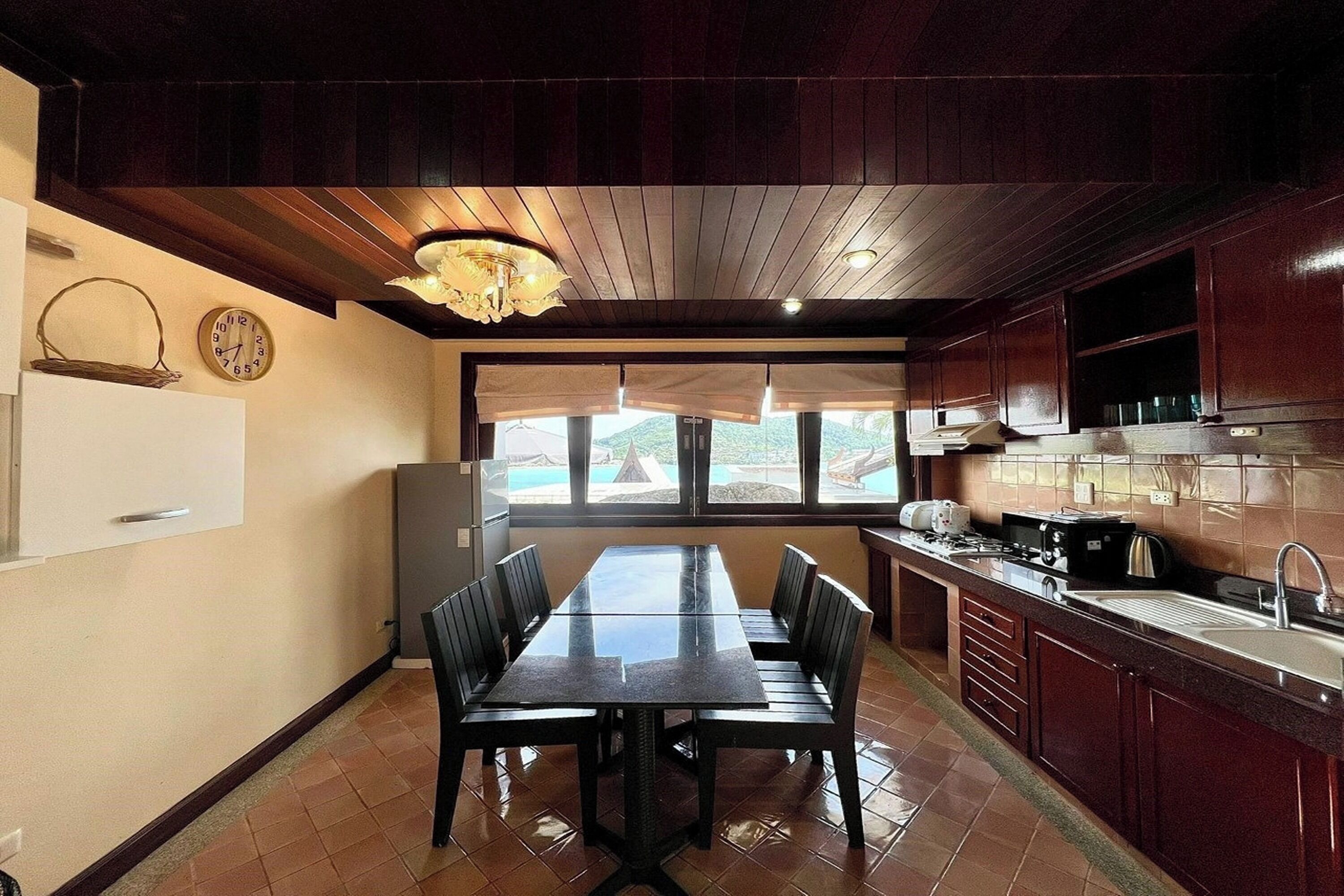 Una cocina con una mesa de comedor, sillas, un refrigerador y una ventana con vistas.
