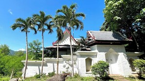 A traditional building with a white facade, red roof, and multiple palm trees in the foreground. - Panorama Ocean Villas, Kamala (Kamala)