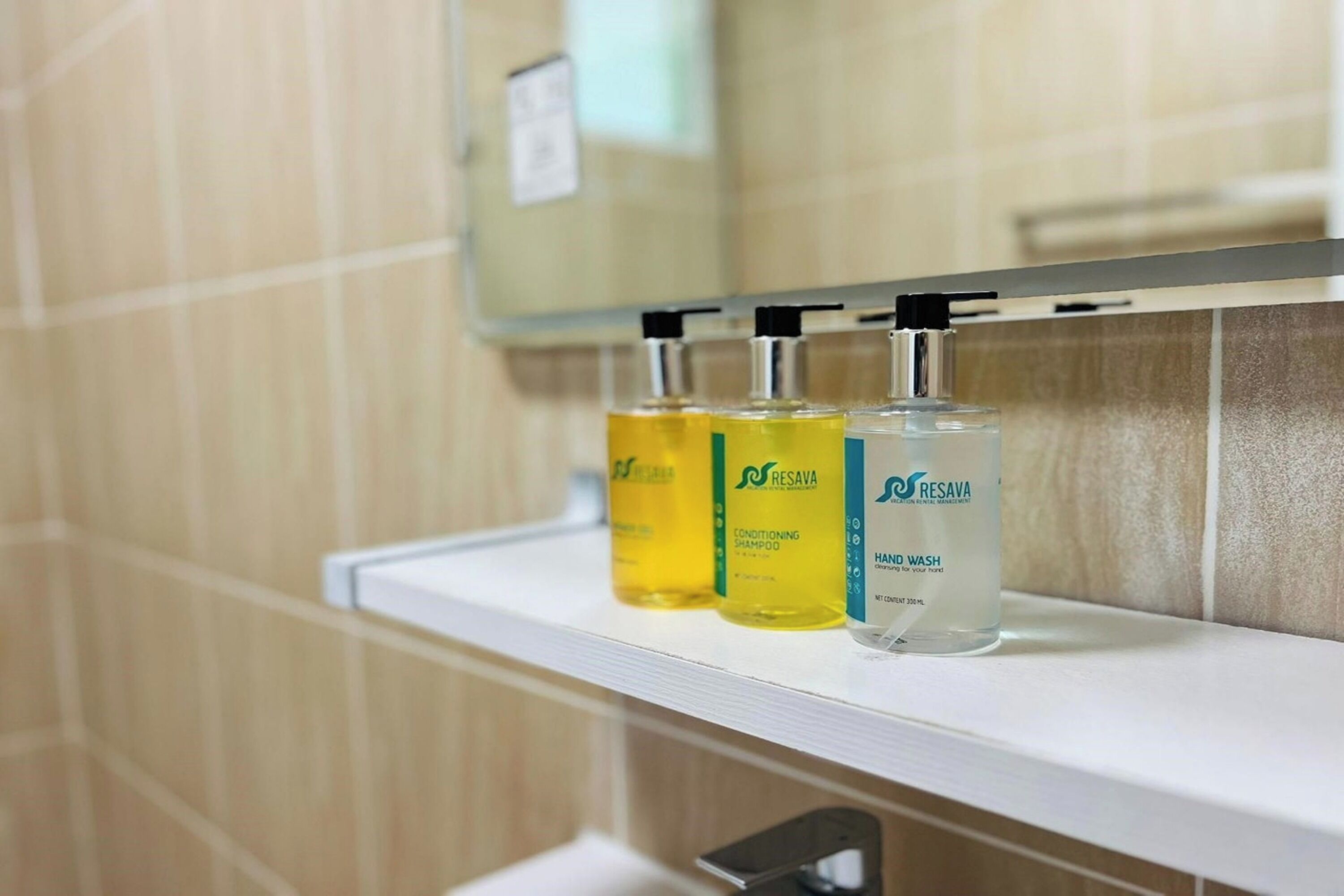 A bathroom shelf with three bottles of shampoo and conditioner.