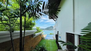 A narrow pathway leading to a pool with a view of a mountain and a body of water. - Panorama Ocean Villas, Kamala (Kamala)