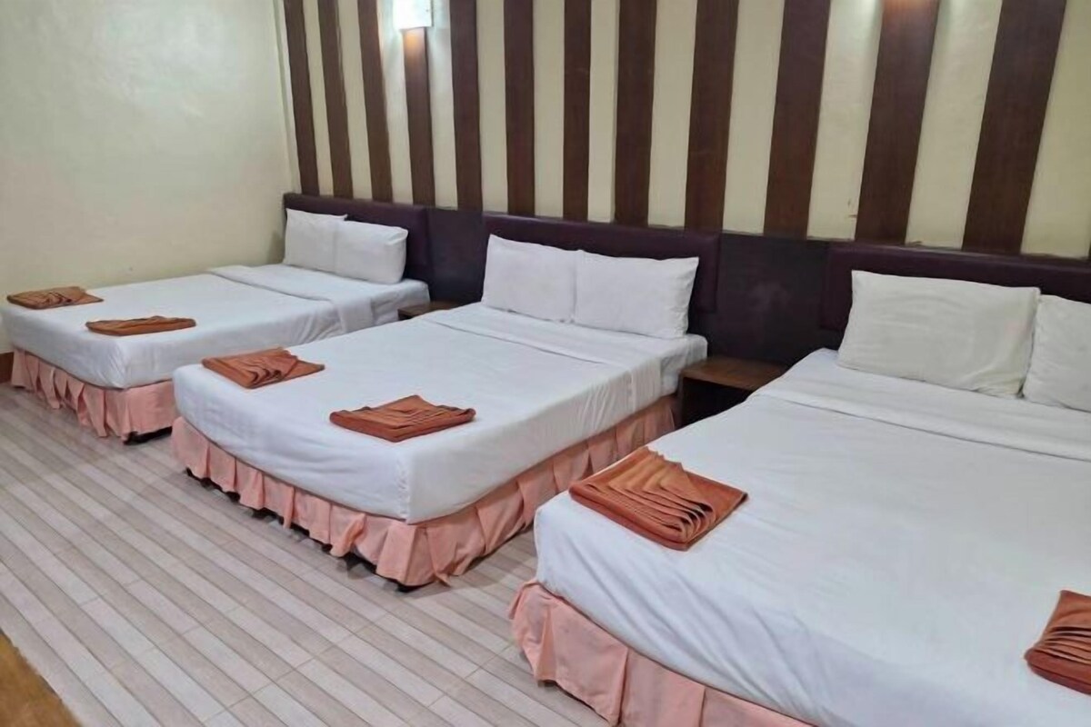 Habitación de hotel con tres camas individuales, cada una con cubrecolchones rosas y ropa de cama blanca.