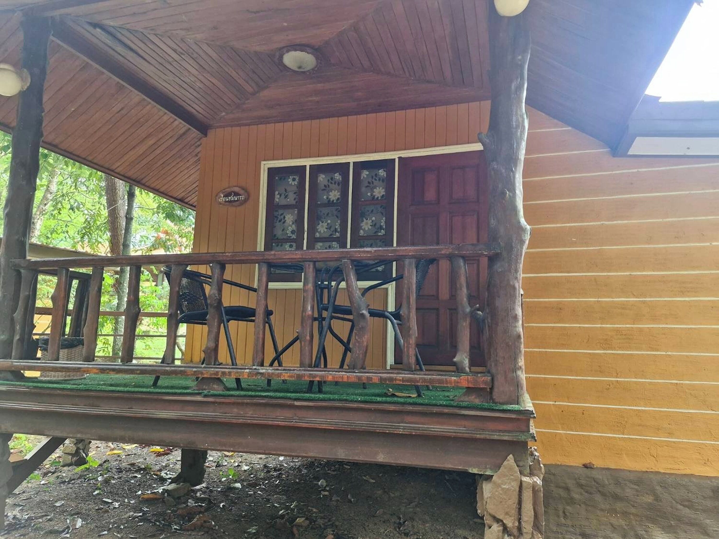 A wooden cabin with a porch, a door with glass panels, and a small outdoor seating area with chairs.