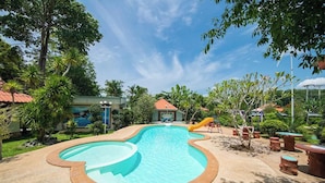A swimming pool with a slide, surrounded by trees and outdoor furniture. - Tontarn Resort And Spa (Khanom)