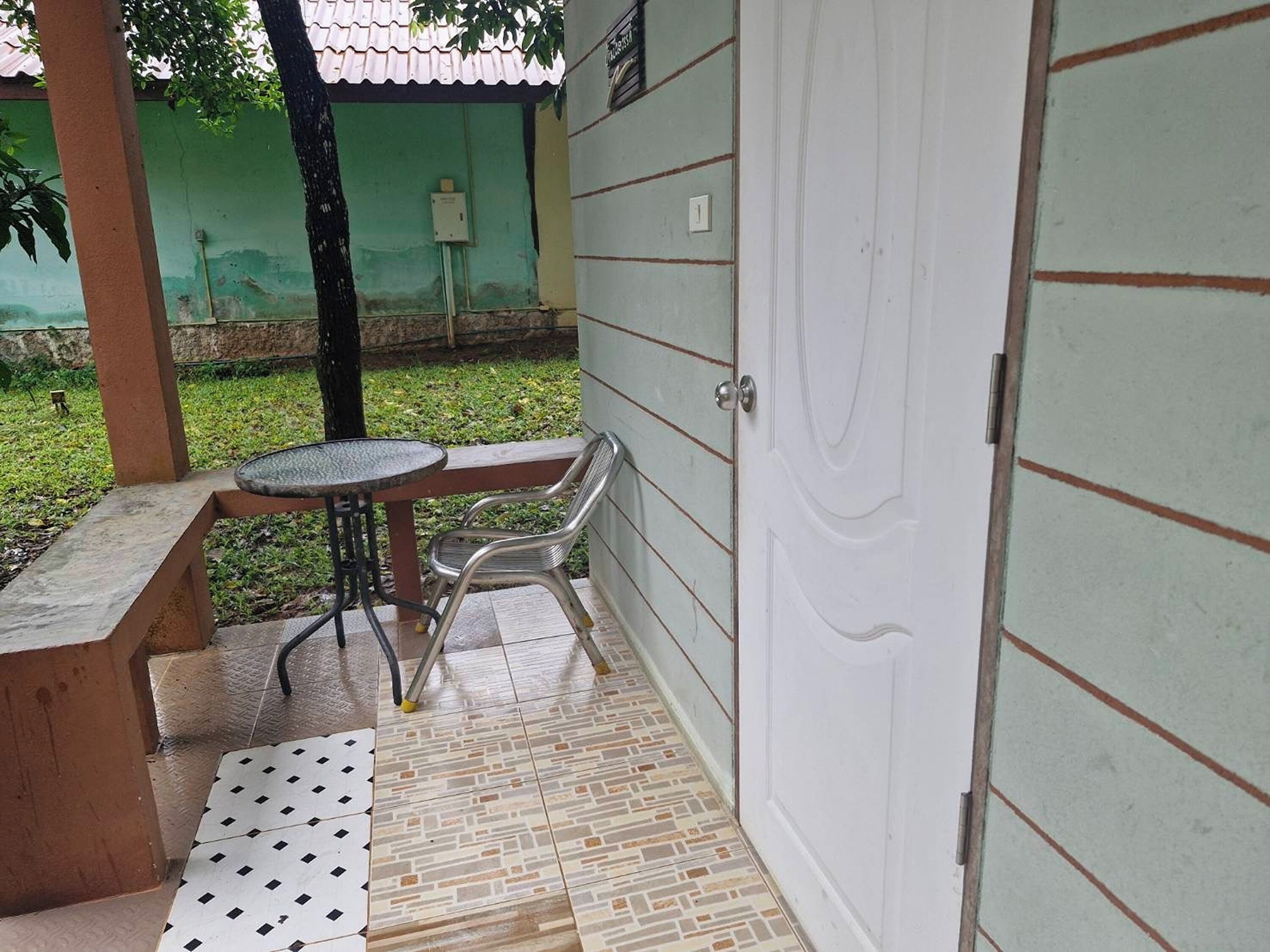Un patio cubierto con una mesa, sillas y un banco, además de piso de baldosas.