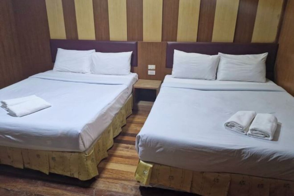 Two twin beds with white linens, wooden headboards, and a striped wall design.