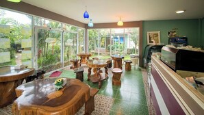 A restaurant with wooden tables and chairs, large windows, and a counter with Pepsi. - Tontarn Resort And Spa (Khanom)