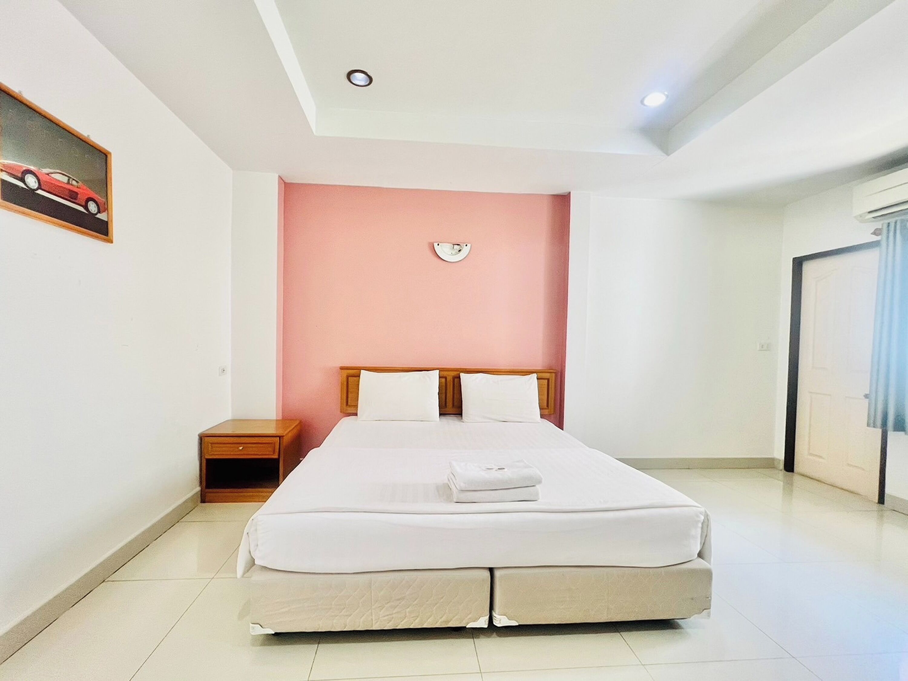 A bedroom with a bed, nightstand, and a wall clock.