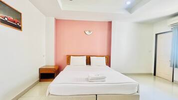 A bedroom with a bed, nightstand, and a wall clock.