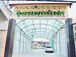 A covered walkway leading to a building with a sign above it. - Udon Perfect Mansion (Udon Thani)