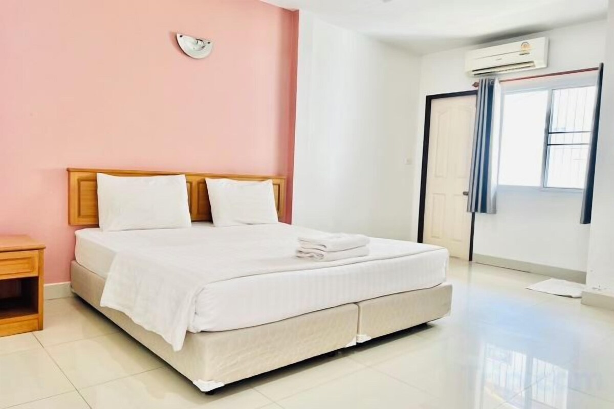 Una habitación de hotel limpia y bien iluminada, con cama, mesita de noche y ventana con cortinas.