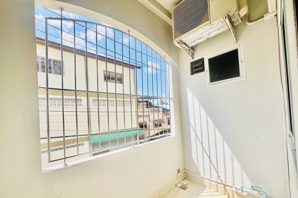 A room with a large window, a small air conditioning unit, and a tiled floor.