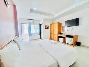 A hotel room with a large bed, a desk with a computer, a TV mounted on the wall, and a wardrobe. - Udon Perfect Mansion (Udon Thani)