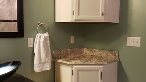 A small bathroom with a white cabinet, a wooden bench, a sink with a black basin, and a towel hanging on a metal ring. - Mountain Chic Cabin Retreat (Woodland Park)