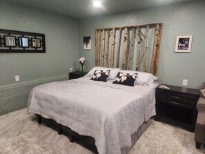 A bedroom with a bed, nightstands, a dresser, a mirror, and wall decorations. - Mountain Chic Cabin Retreat (Woodland Park)